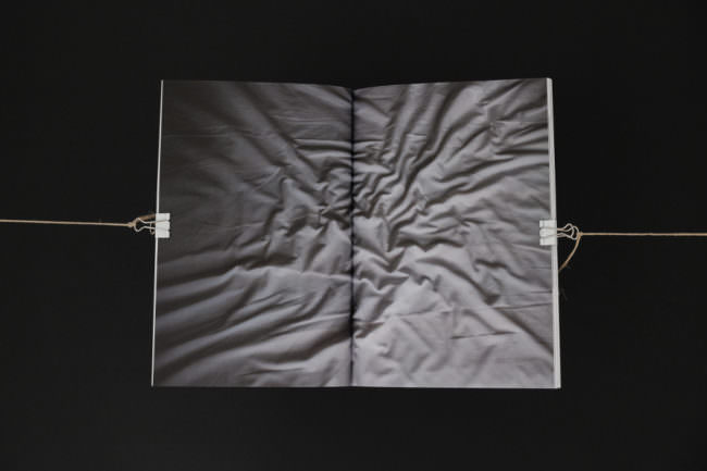 Eine zerknüllte Bettdecke auf einer Doppelseite eines Buches.