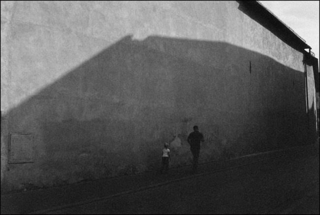 Ein Mann und ein Kind im Schatten der Wand.