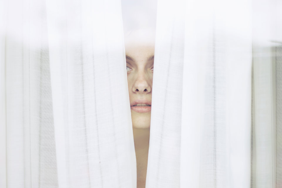 Eine Person schaut durch eine Lücke in einem Vorhang