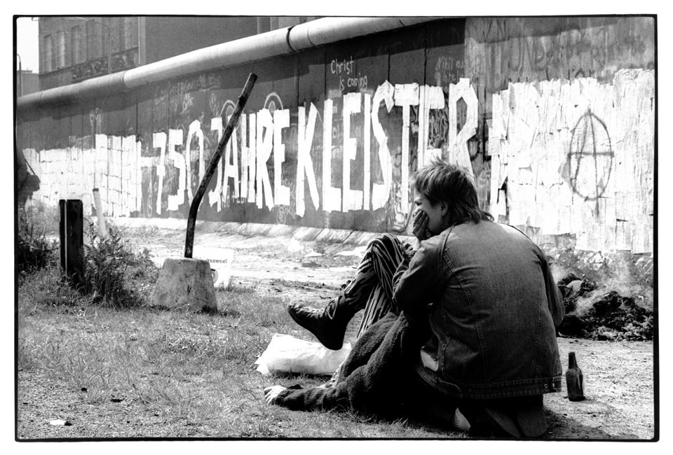 Ein Jugendlicher sitzt an einer Mauer.