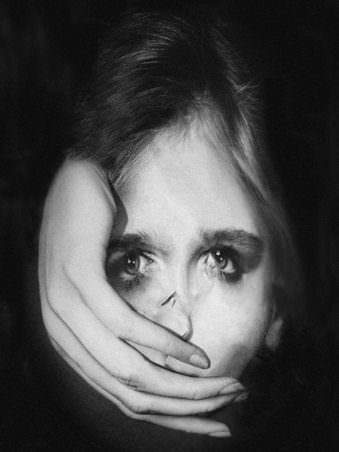 Portrait einer Frau in schwarz weiß welche eine Hand vor dem Mund hat.