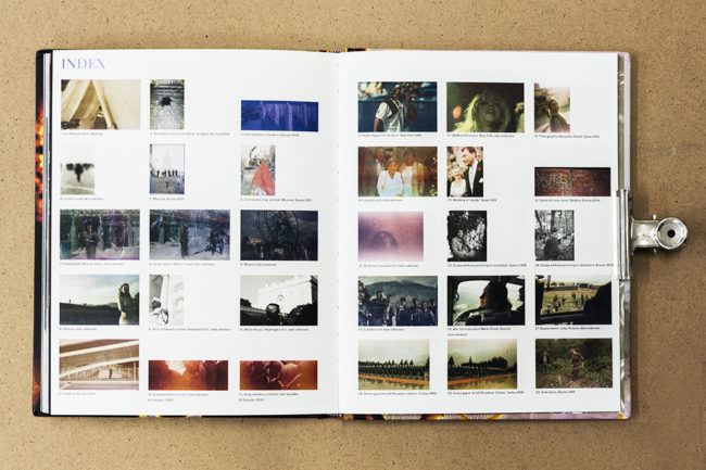 Aufgeschlagenes Buch mit Doppelseite voller farbiger Indexfotografien