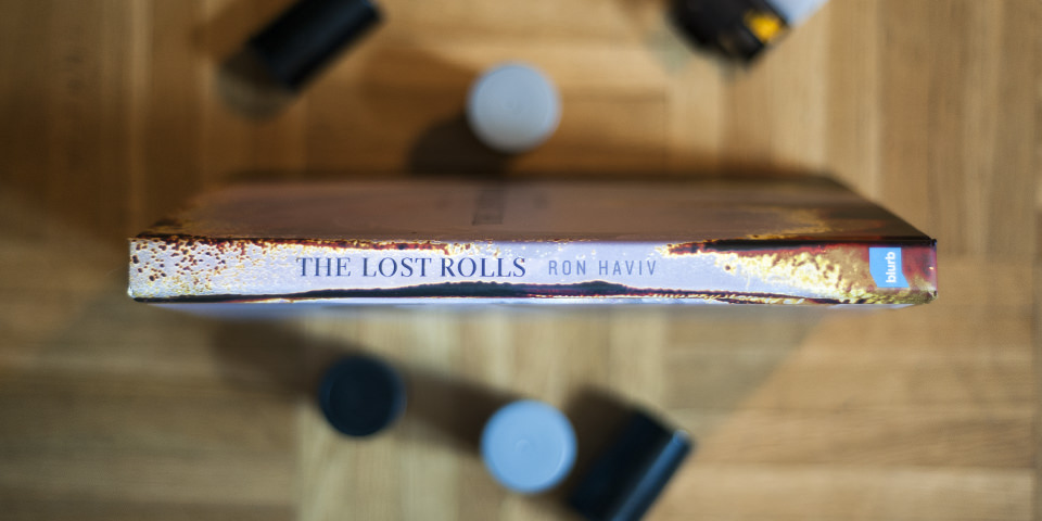 Buchrücken Abbildung von The Lost Rolls mit Filmdosen dekoriert auf Holzfußboden
