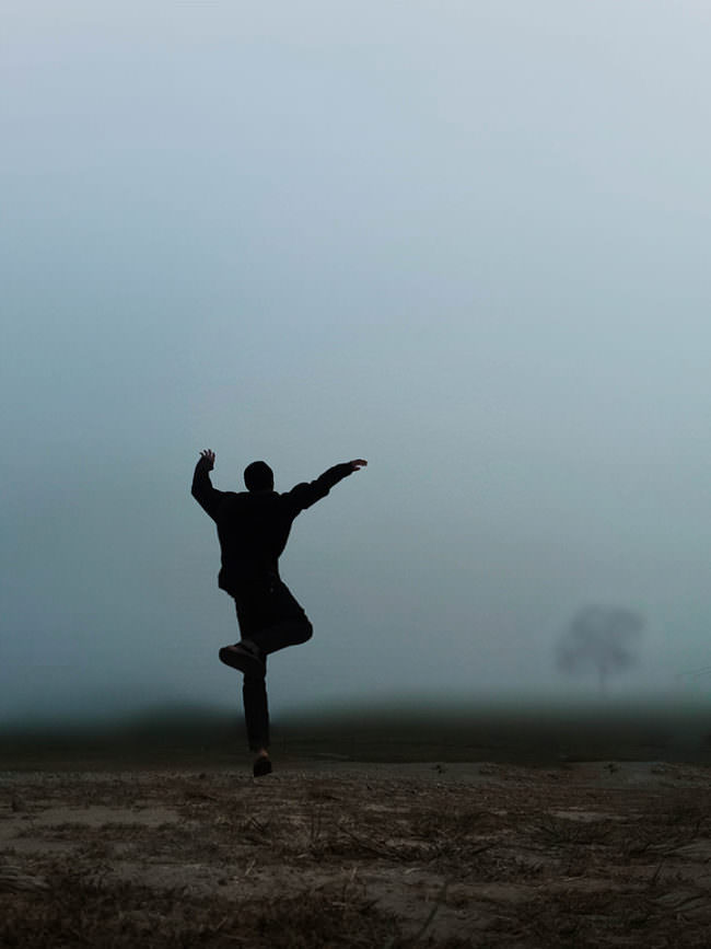 Eine Person tanzt auf einem nebeligen Feld.