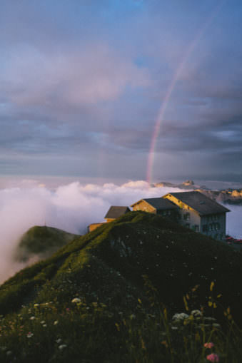 Ein Haus auf einem Berggipfel unter einem Regenbogen