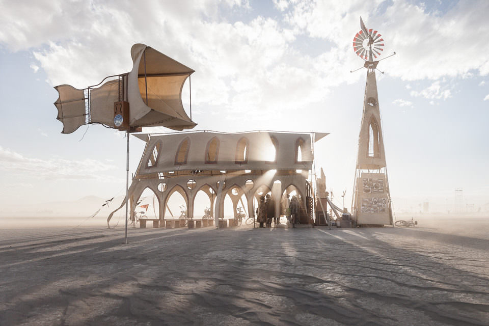 Ein Gebäude und ein Windrad in der Wüste.