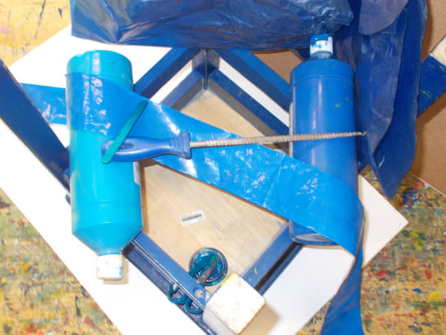 Ansammlung blauer Gegenstände, Plastikband, Pinsel, Stuhlunterseite und Farbtuben.