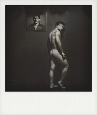 Polaroid von einem Portrait als Gemälde an der Wand vor dem ein Mann nackt vorbeigeht.