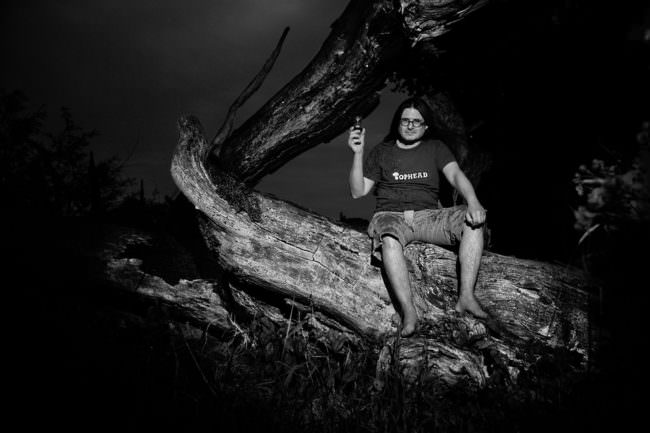 Mann sitzt auf abgestorbenem Baumstamm