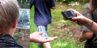 Hinterkopf eines jungen mit Tablett im Wald und Kinder die etwas auf einer Hand fotografieren.