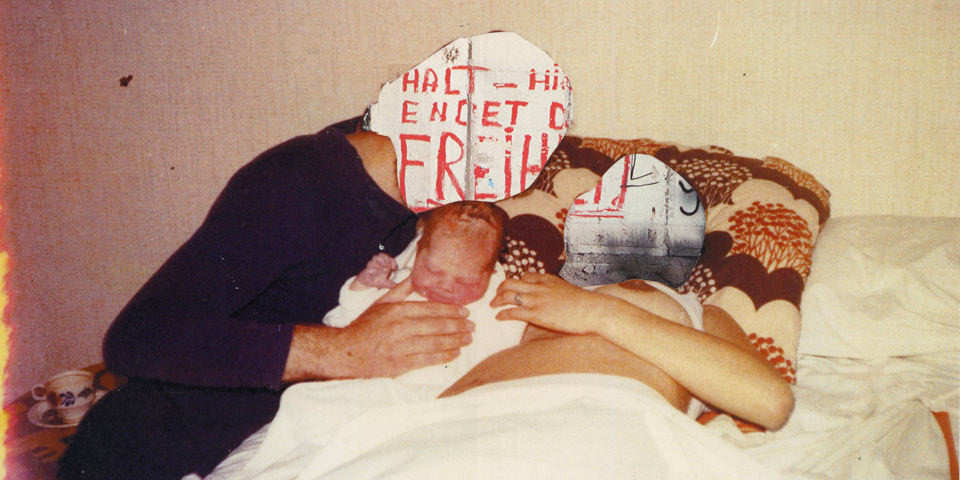 Ansicht einer alten Fotografie von einem Paar mit Baby auf einem Bett mit überklebten Köpfen.