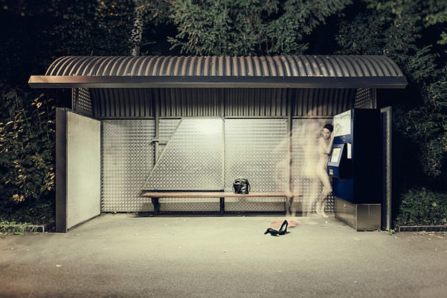 Aktaufnahme einer Frau an einer Bushaltestelle mit Langzeitbelichtung.