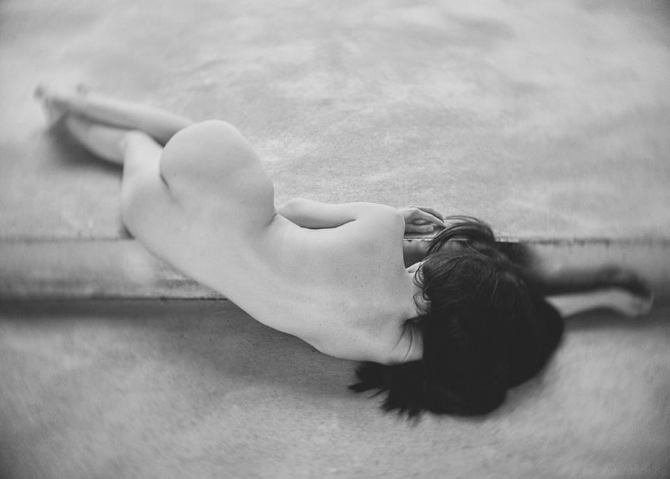 Eine Frau liegt nackt auf einem Betonboden