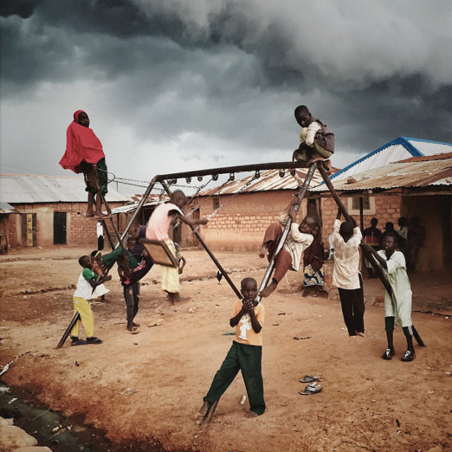 Acht Kinder spielen auf einem Schaukelgerüst unter freiem Himmel.