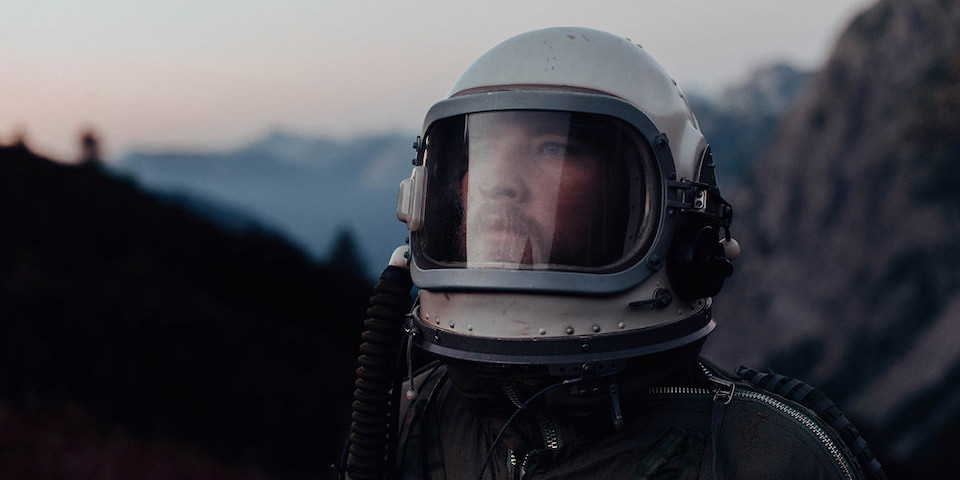 Portrait eines Astronauten vor einer Berglandschaft.