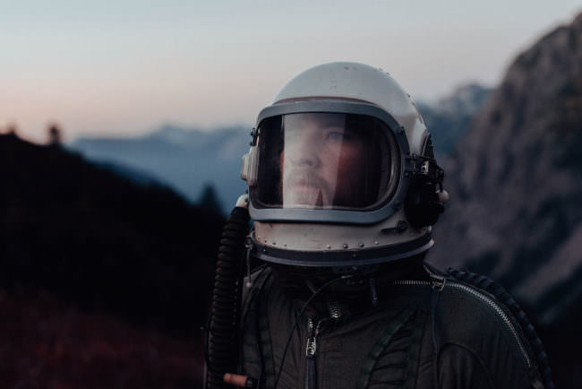 Portrait eines Astronauten vor einer Berglandschaft.