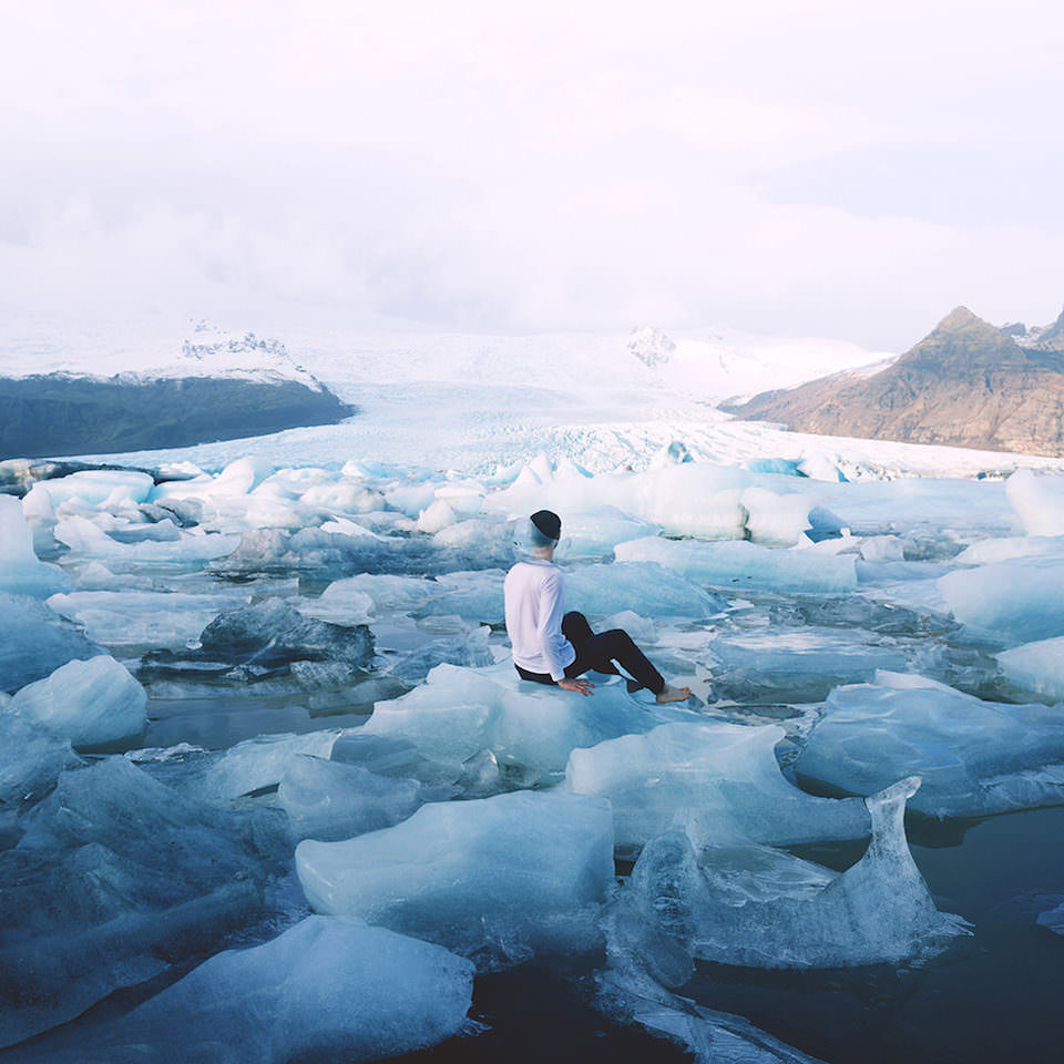 Ein Mann sitzt inmitten einer Eislandschaft und hat ein kaputtes Fischglas auf dem Kopf.