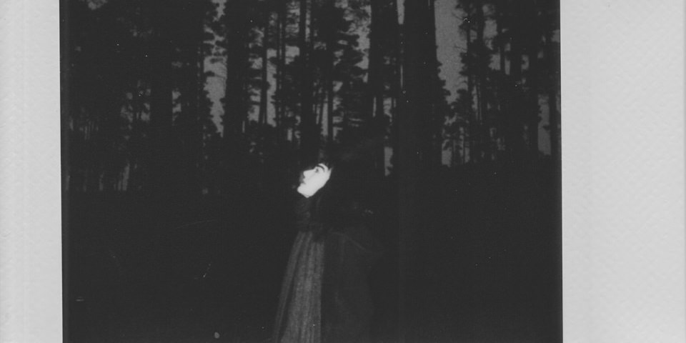 Eine Person steht vor dunklen Bäumen