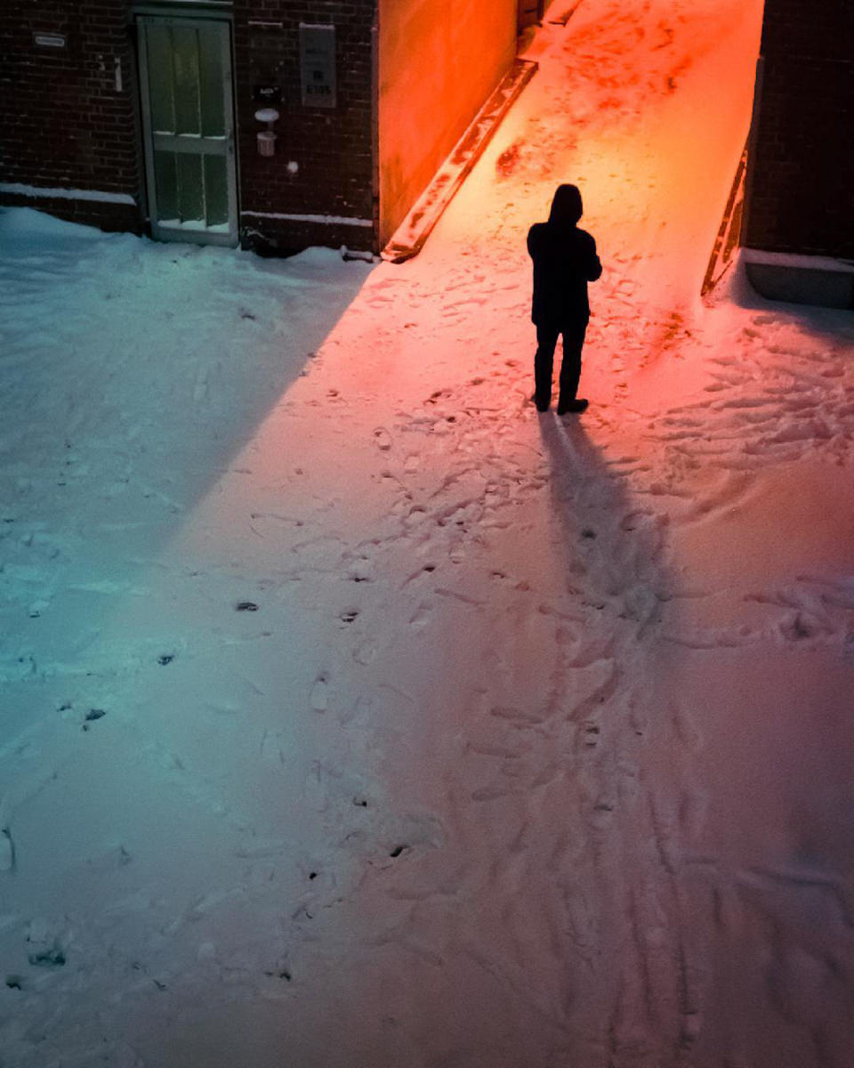 Eine Person steht in einer beleuchteten, verschneiten Straße
