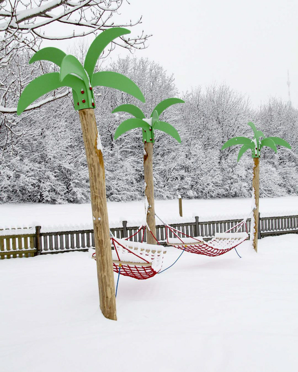 Hängematten hängen künstlichen Palmen in verschneiter Landschaft