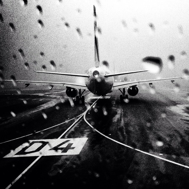 Sicht durch eine nasse Scheibe auf ein Flugzeug auf der Rollbahn.
