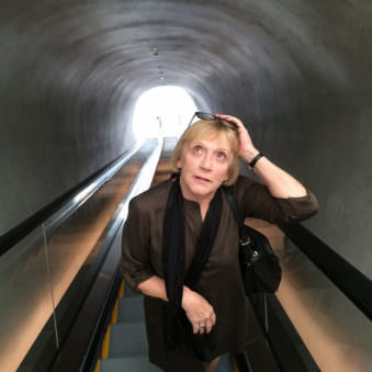 Frau auf einer Rolltreppe in einem Tunnel von vorn fotografiert.