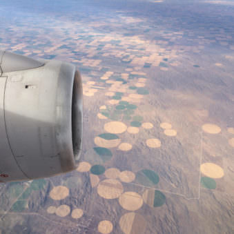 Sicht auf einem Flugzeug mit angeschnittener Turbine und runden Feldern am Boden.