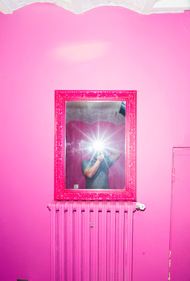 Selbstportrait im Spiegel an einer pinken Wand