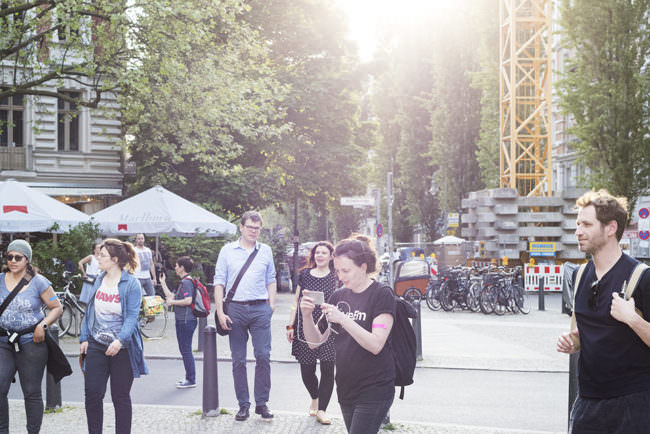 Gruppe von Personen im Sonnenlicht laufend fotografiert in einer Stadtszenerie.