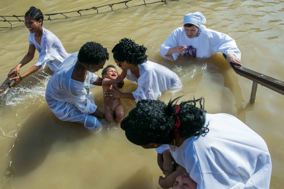 Menschen in weiß taufen einen Säugling