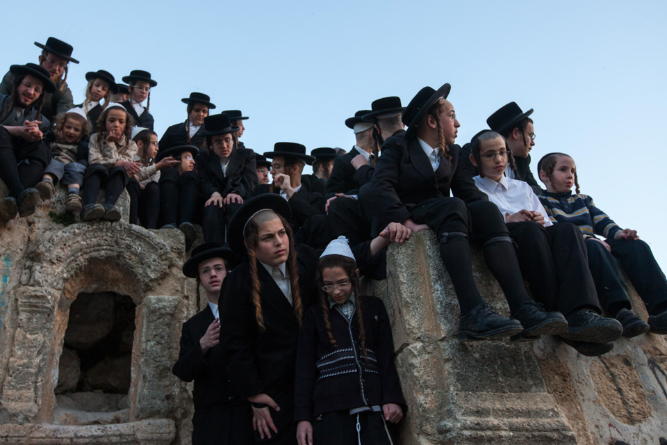 Orthodox-jüdische Kinder sitzen auf einer Mauer