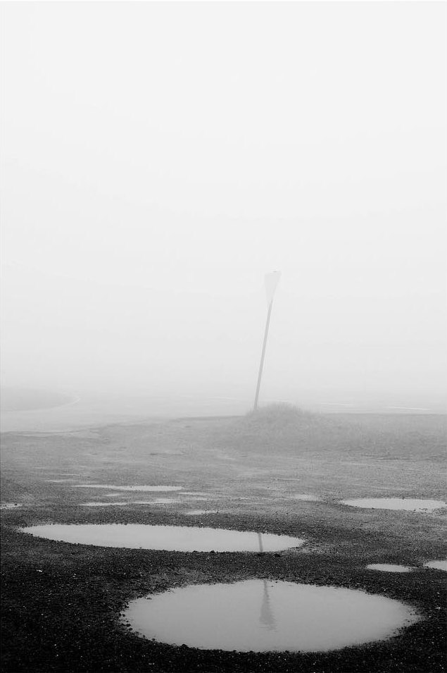 Karge Landschaft mit großen Pfüten im Nebel.