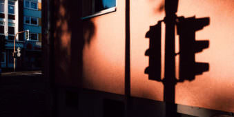 Schatten einer Ampel, der auf ein rotes Haus fällt.
