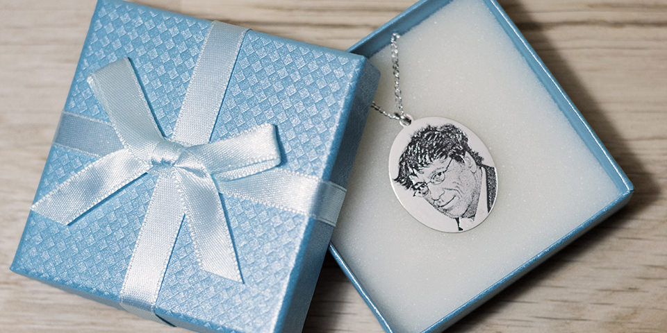 Fotogravurkette mit Portrait in einer blauen Geschenkverpackung.