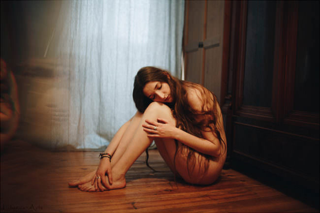 Eine Frau sitzt nackt auf dem Boden