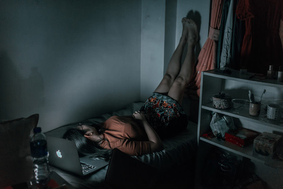 Ein Mädchen liegt mit den Beinen nach oben im Bett