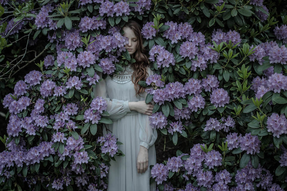 Frau in einem Busch mit lila Blüten