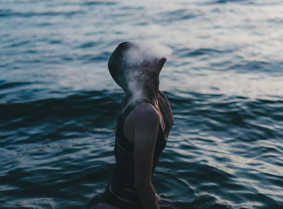 Eine Frau im Meer mit Rauch über dem Gesicht