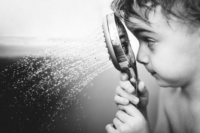 Ein Kind spielt mit einem Duschkopf