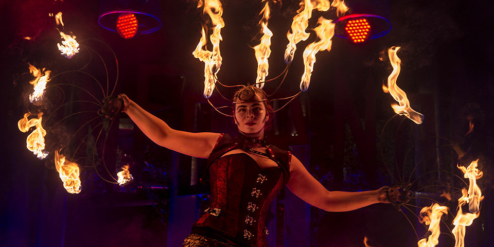 Eine Frau in Kostüm mit brennenden Fächern.
