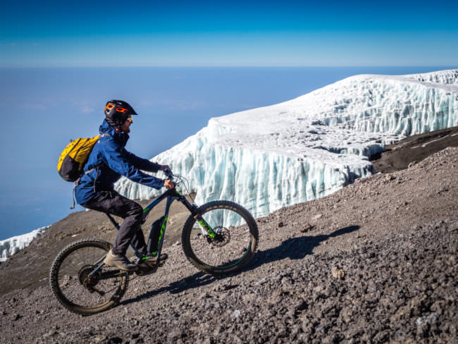 Mann auf einem Rad fährt neben Gletschereis