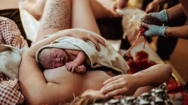 Neugeborenes auf dem Bauch der Mutter