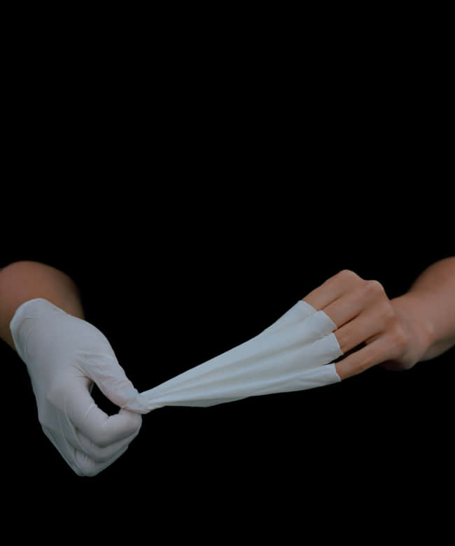 Hände, die weiße Handschuhe ausziehen.