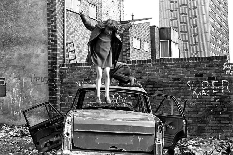 Ein Mädchen springt auf einem kaputten Auto