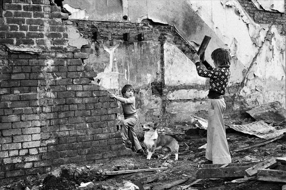 Kinder spielen an einem kaputten Haus