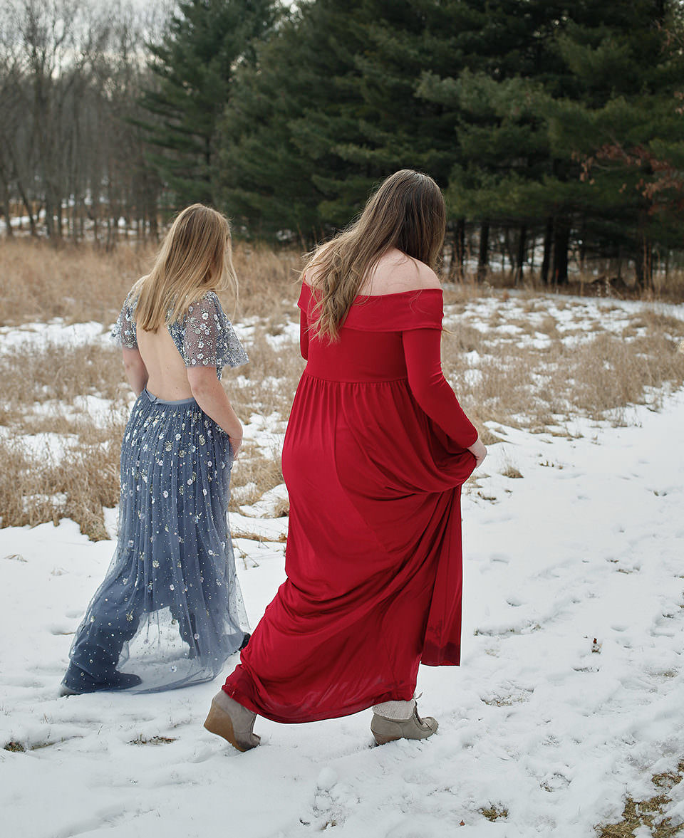 Zwei Frauen in Abendkleidern laufen durch eine Winterlandschaft