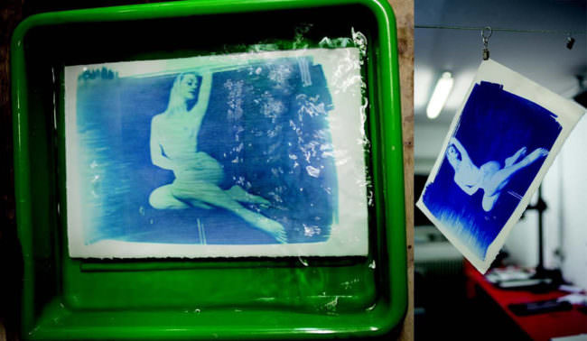 Bild einer Frau im Akt in blau in einer Entwicklerwanne und an einer Trockenleine.