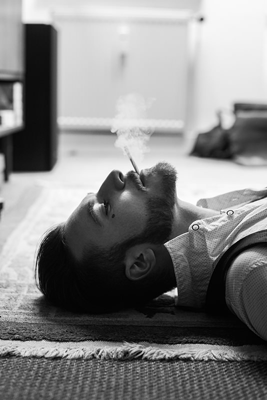 Mann liegt rauchend auf dem Boden