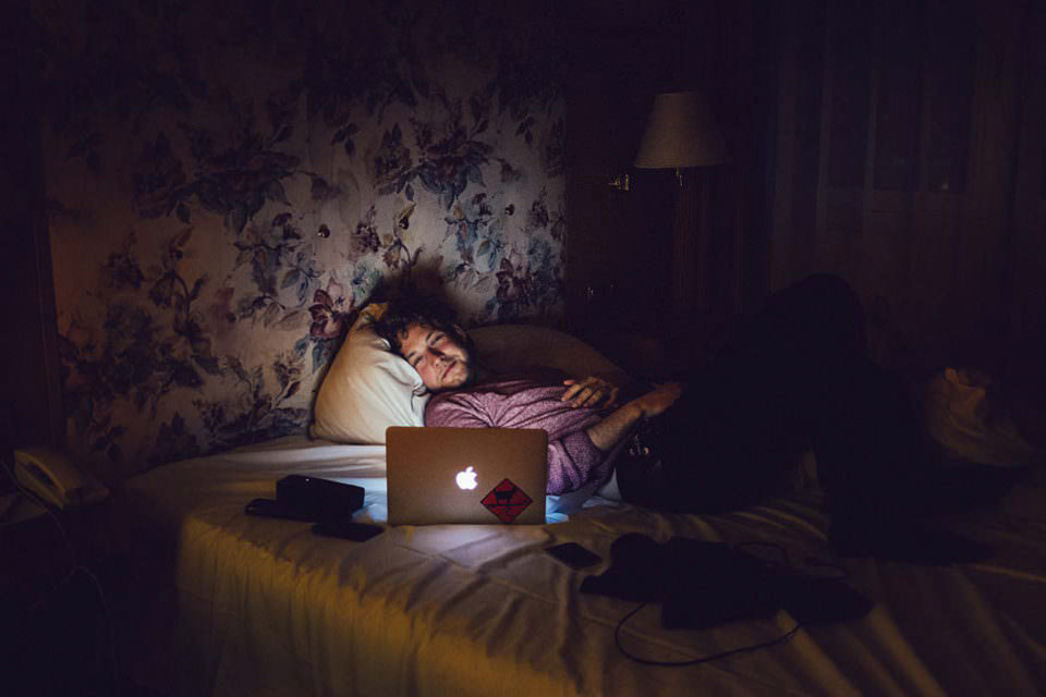 Mann mit Laptop im Bett