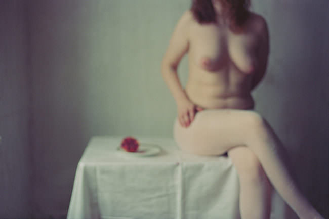 Eine Frau sitzt auf einem Tisch mit einem Granatapfel